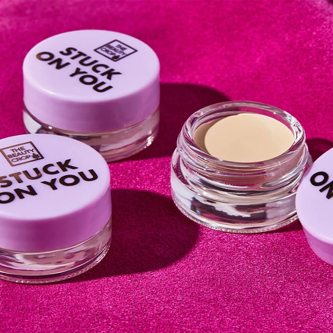 Three pots of THE BEAUTY CROP Stuck On You Eyeshadow Primer on fuchsia textile Desktop