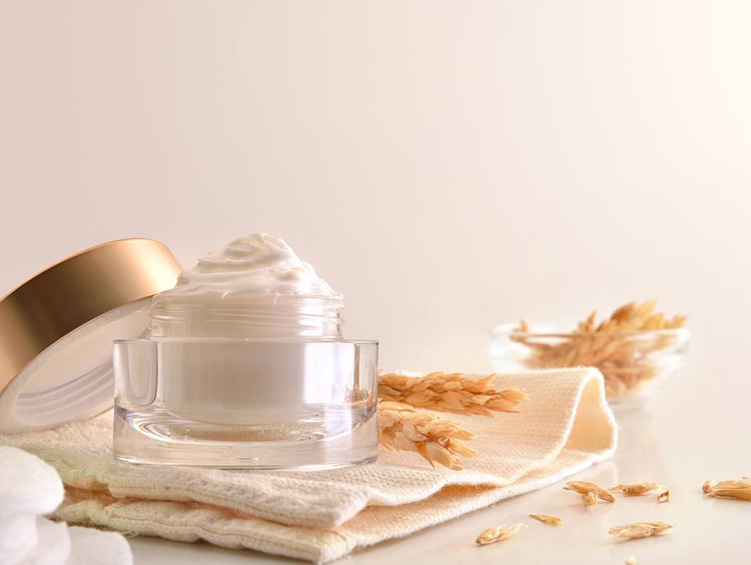 A photo of a full tub of oat cream and oat stalks on a beige cloth Desktop