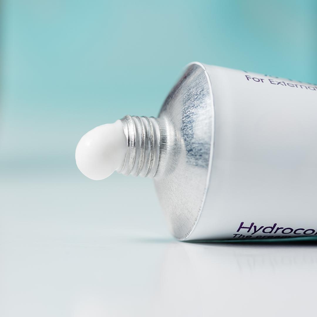A tube of hydrocortisone cream on a domestic bathroom top with a blue background Desktop