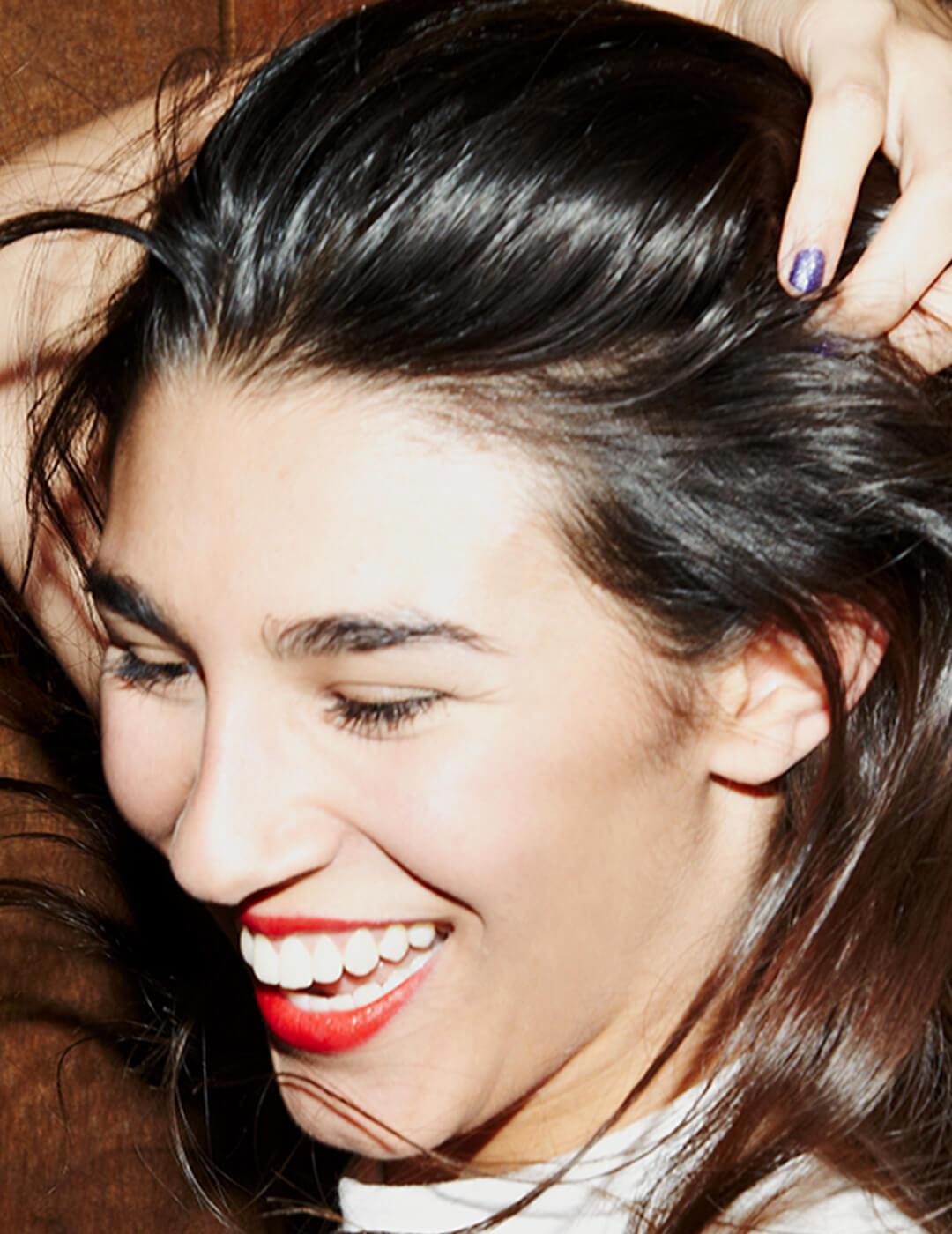 An image of a woman happily holding her hair on a mahogany wall Desktop