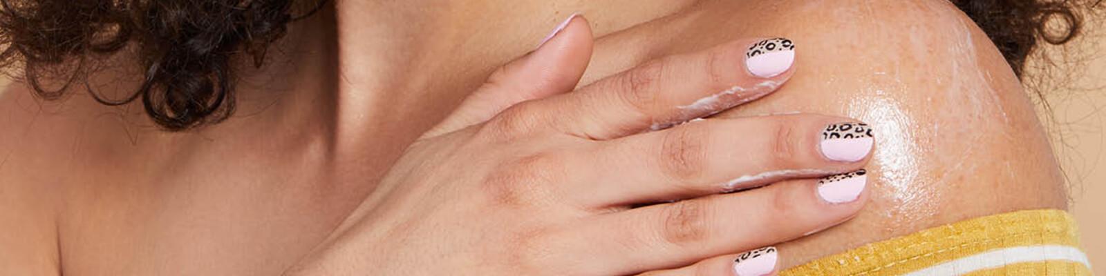 Close-up image of a model's hand putting lotion on shoulder Desktop