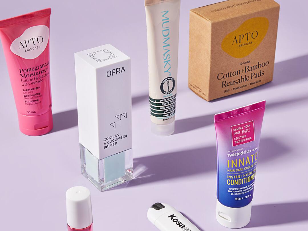 Makeup, skincare, and hair care products standing on purple background Desktop