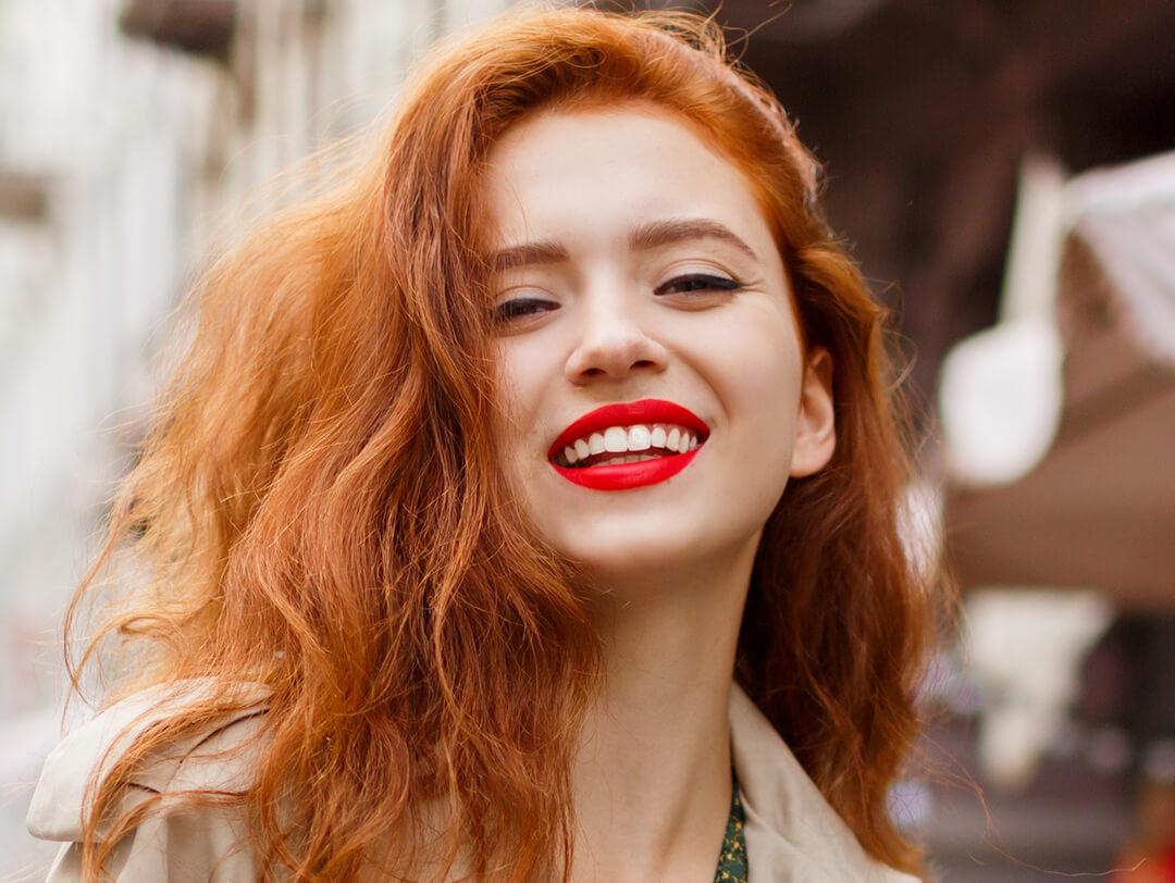 Portrait of a beautiful woman with red hair and natural makeup look with red lips on the street Desktop