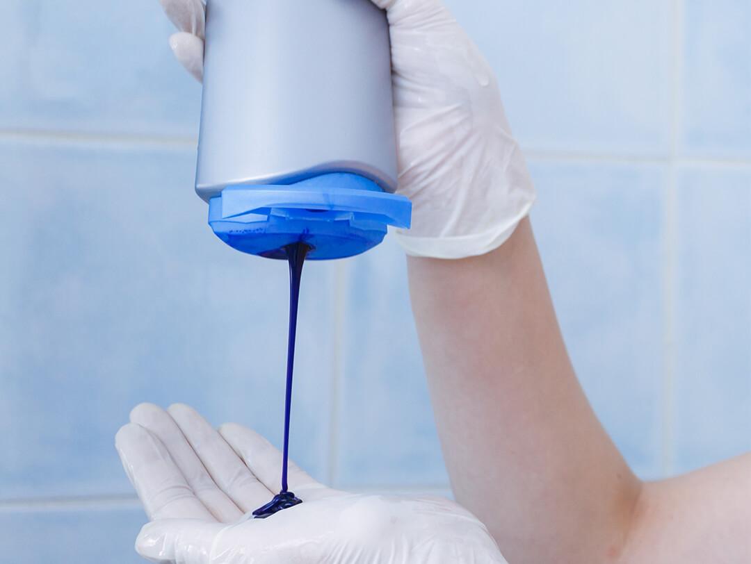 Image of a woman's hands with latex gloves pouring blue shampoo Desktop
