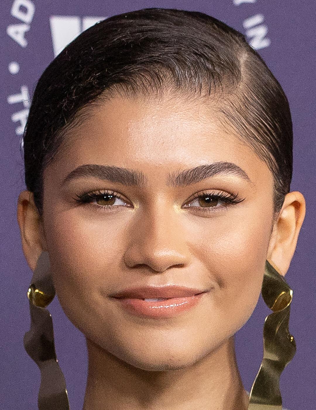 A photo of Zendaya with a neutral makeup look, wearing gold earrings Desktop