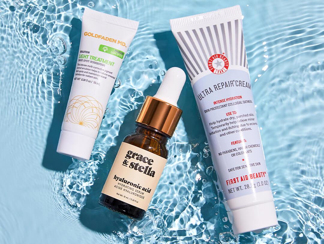 GOLDFADEN MD Light Treatment - Dark Spot Corrector, GRACE & STELLA Hyaluronic Acid Serum, and FIRST AID BEAUTY Ultra Repair® Cream half submerged in water Desktop
