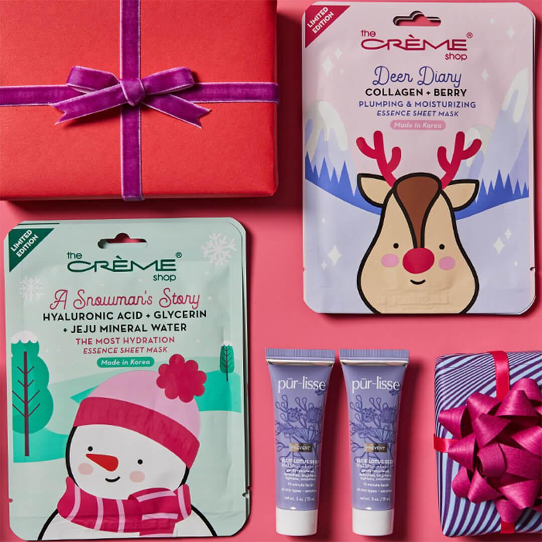 Flat lay image of THE CRÈME SHOP Holiday Sheet Mask Duo - A Snowman's Story + Deer Diary, two tubes of PURLISSE BEAUTY BLUE LOTUS Seed Mud Mask + Exfoliant, and colorful gift boxes on pink background Mobile