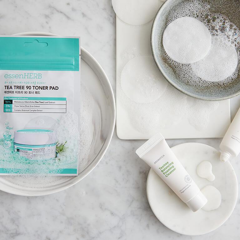 A flatlay image of the AROMATICA Tea Tree Balancing Foaming Cleanser and bubbly toner pads in a dish Mobile
