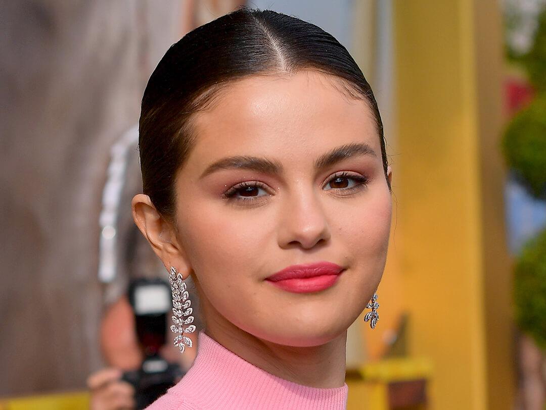Close-up look of Selena Gomez wearing a minimal makeup look sporting a sleek half up, half down hairdo, with her silver droplet dangle earrings Desktop
