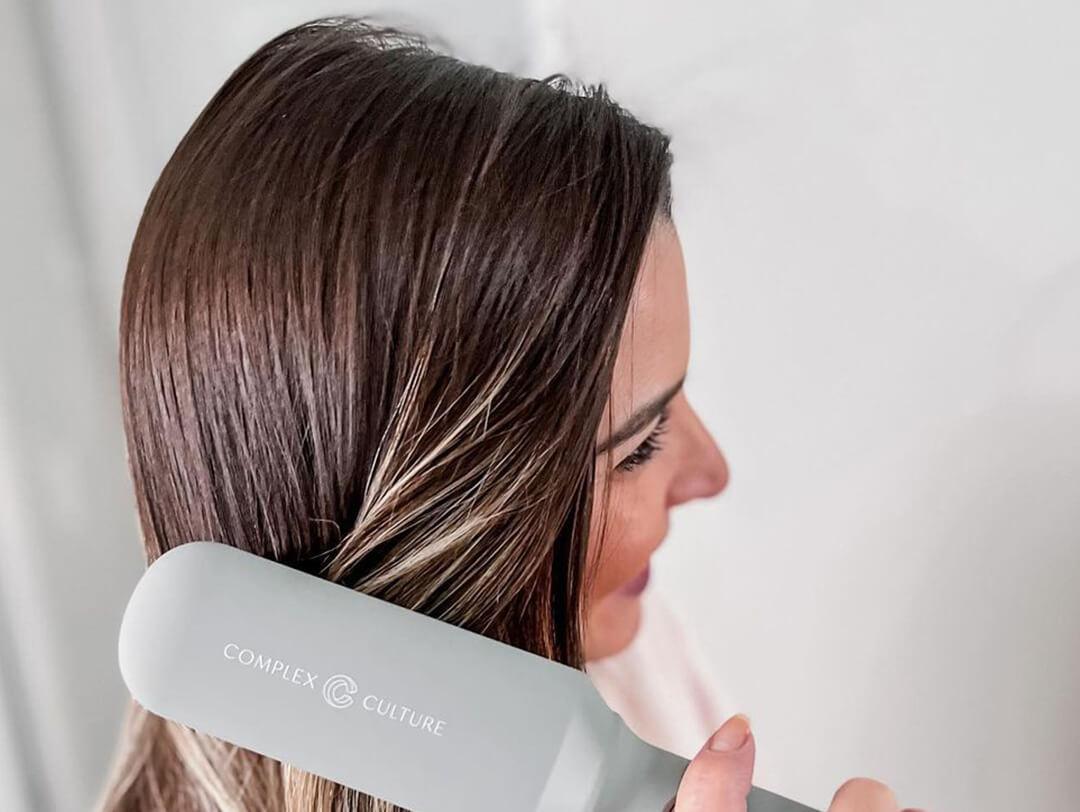 Young woman brushing her hair with the COMPLEX CULTURE Smooth & Straightening Brush Desktop