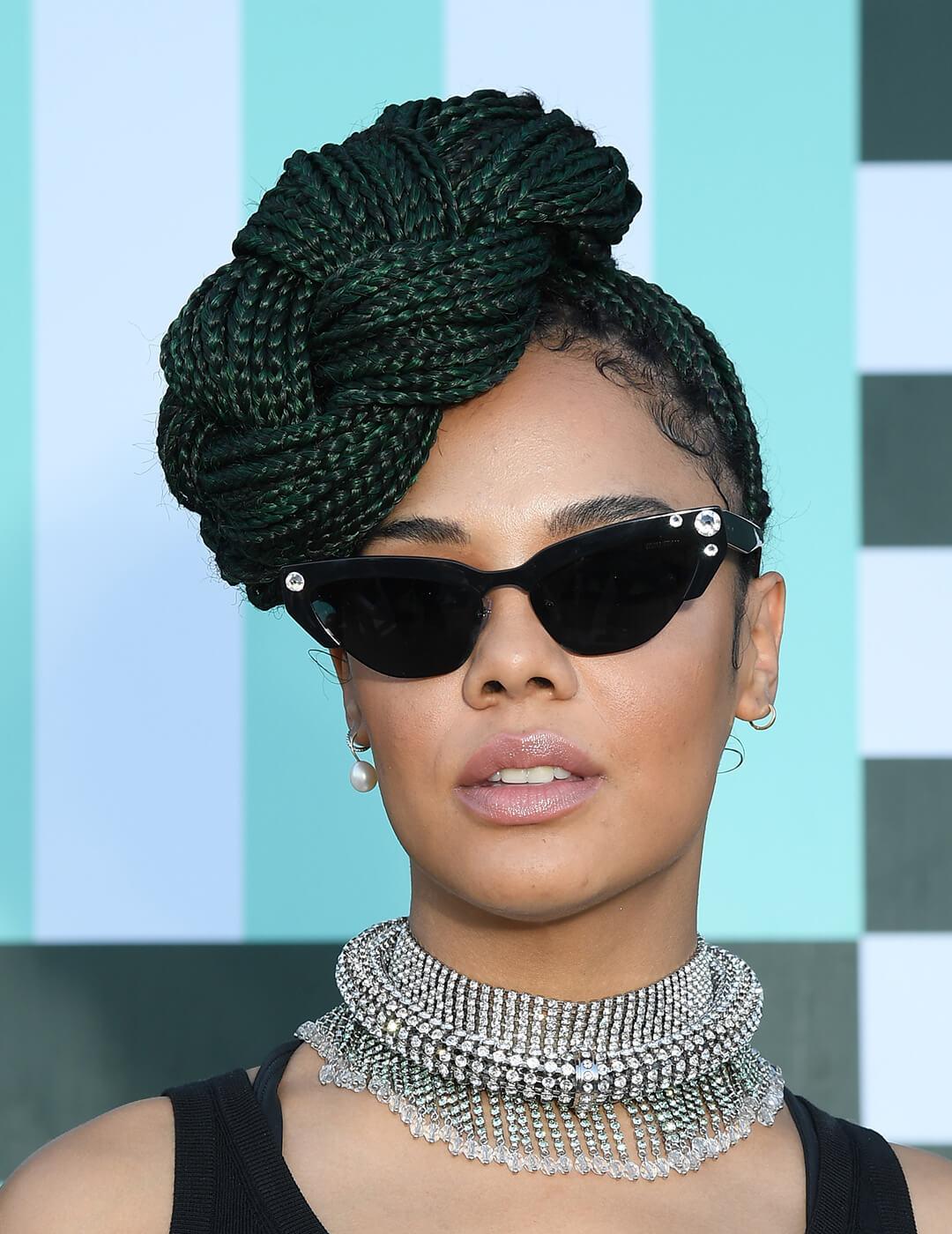 Tessa Thompson rocking a braided bun hairstyle, black dress, and silver choker Mobile