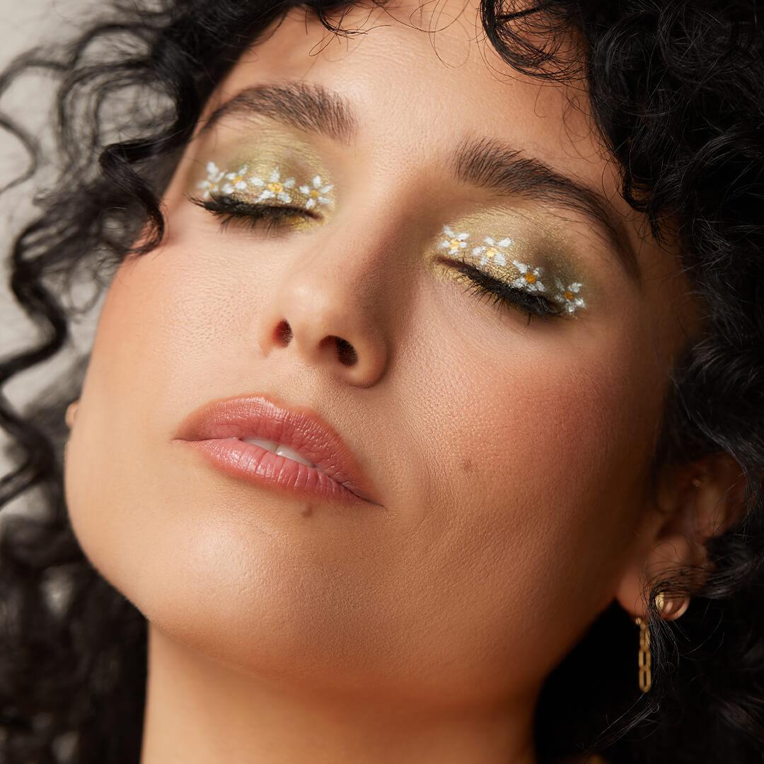 Close-up of a model posing and rocking a green eyeshadow and white daisies makeup look Mobile
