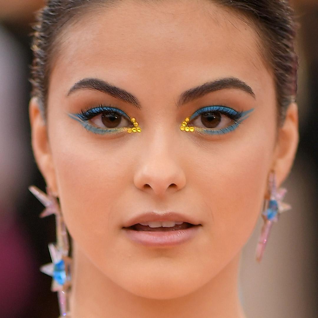 A photo of Camila Mendes with yellow rhinestones and a turquoise double wing eyeliner Mobile