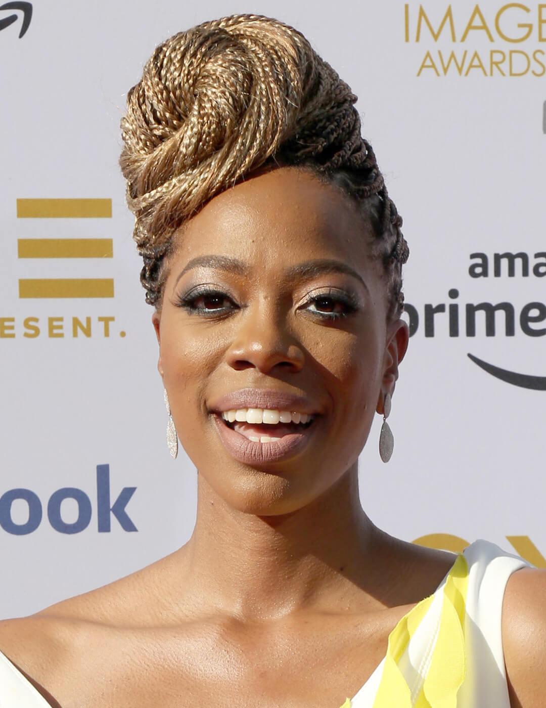 Yvonne Orji rocking a yellow and white dress and braided spiral bun hairstyle Mobile
