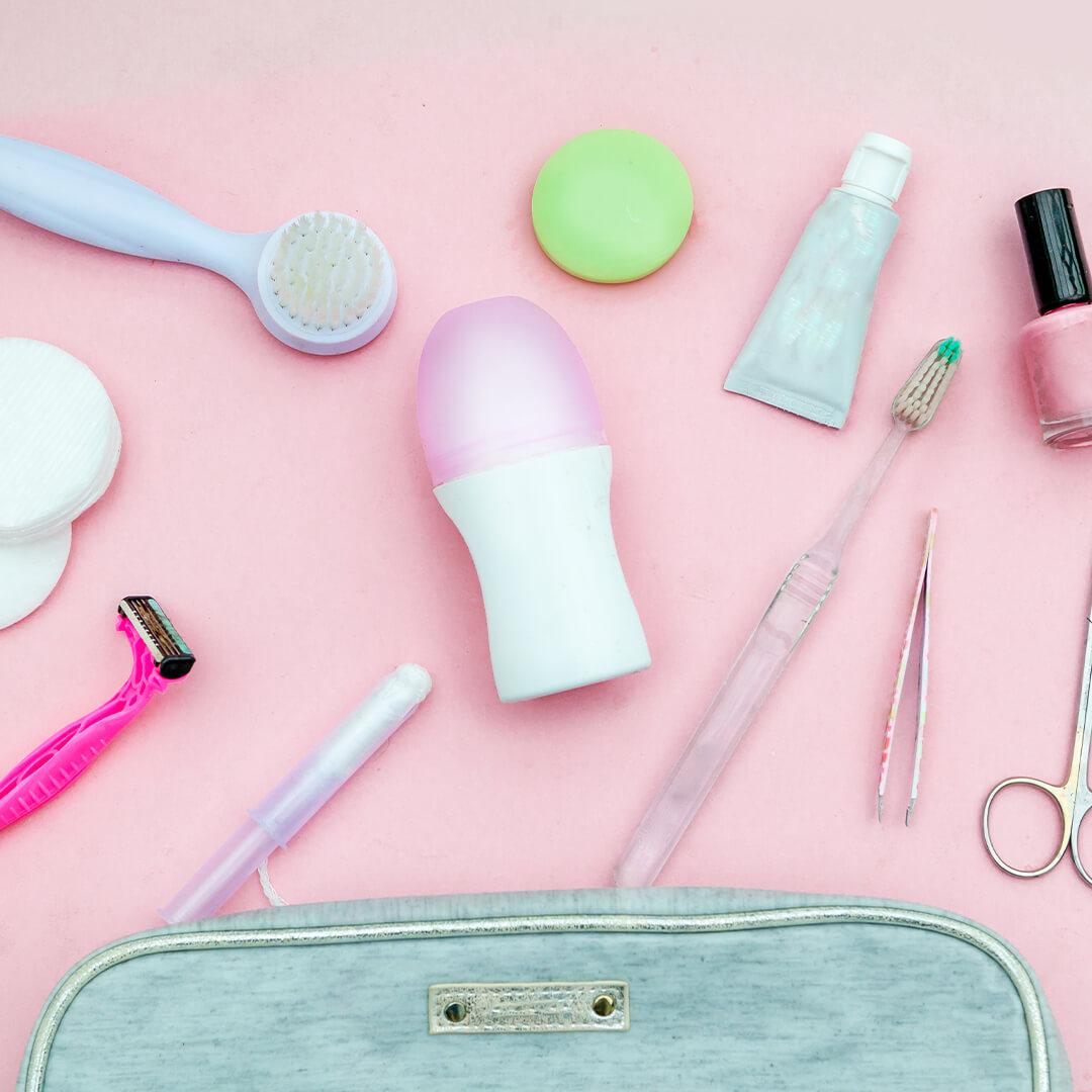 Top view of small teal pouch with hygiene products against pink background Desktop