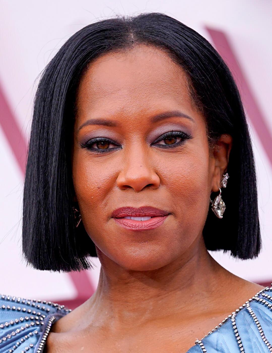 A photo of Regina King showcasing her straight, black bob haircut on a pink background Mobile