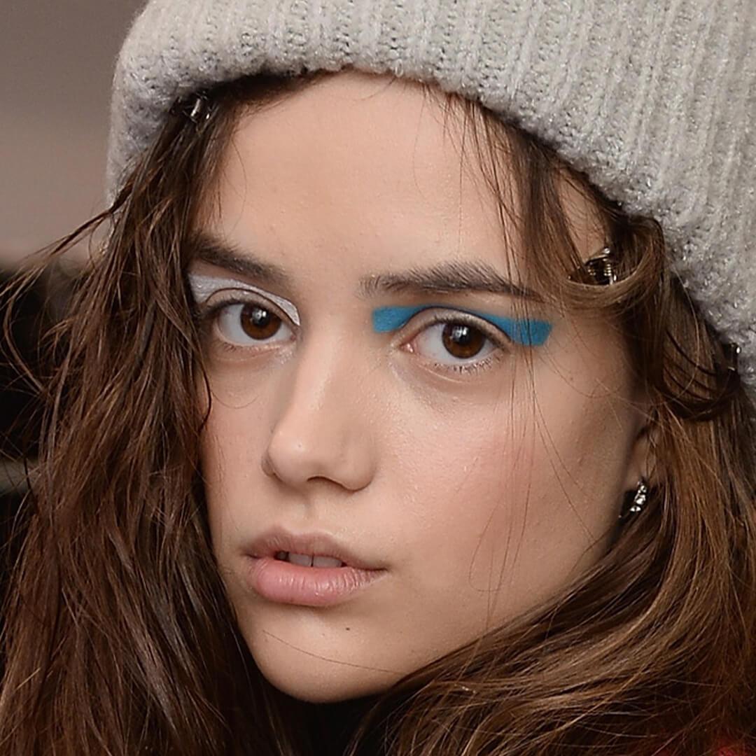 Close-up image of a model wearing a grey beanie rocking a multi-colored eyeshadow look Desktop
