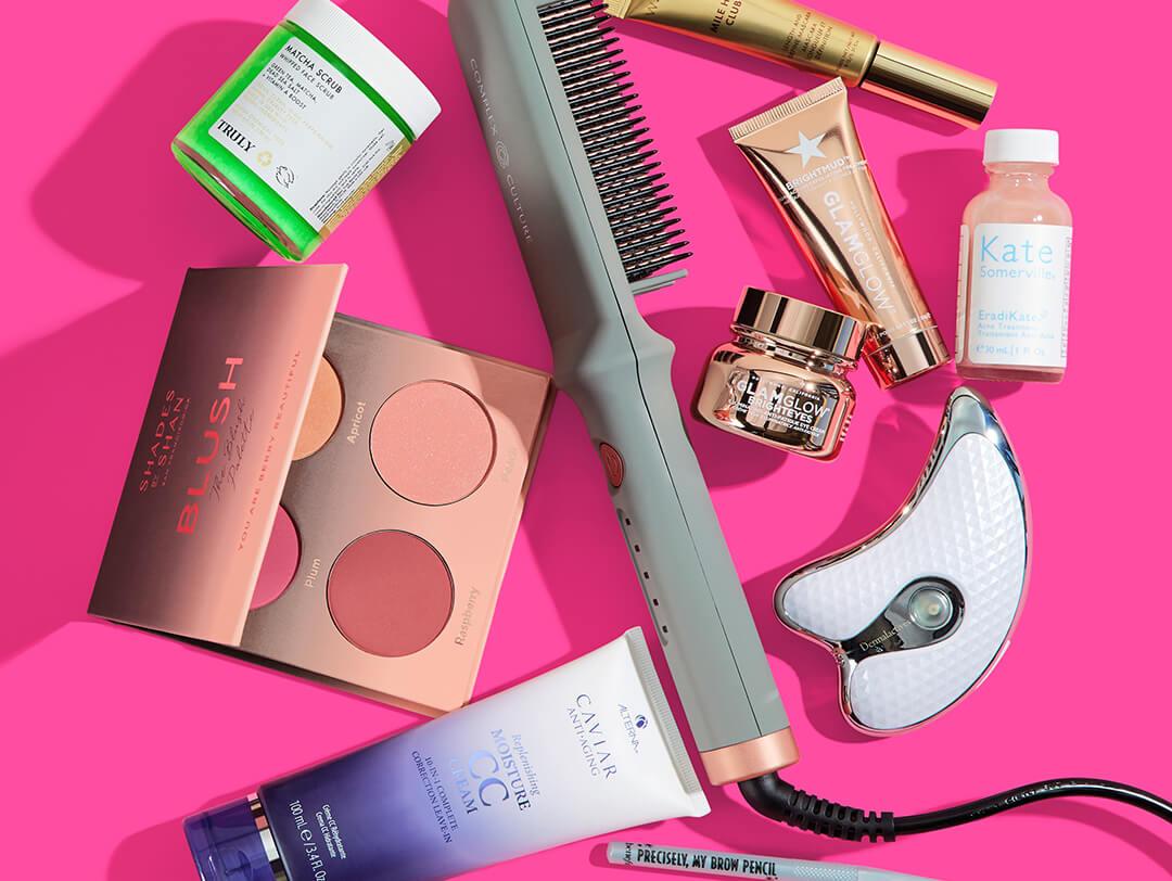 Makeup, skincare, and beauty products and tools from various brands scattered on fuchsia background Desktop