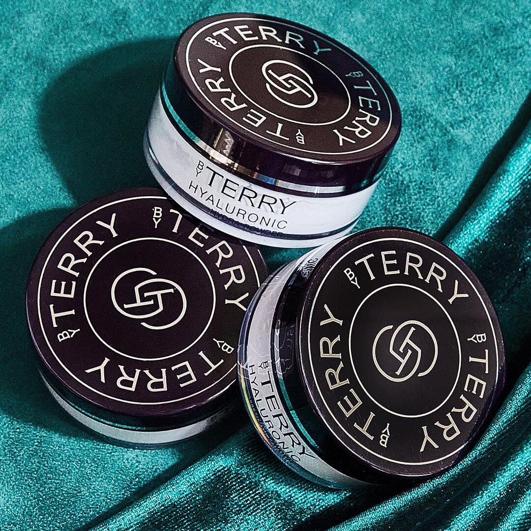 Three jars of BY TERRY Hyaluronic Hydra-Powder on green velvet cloth Desktop