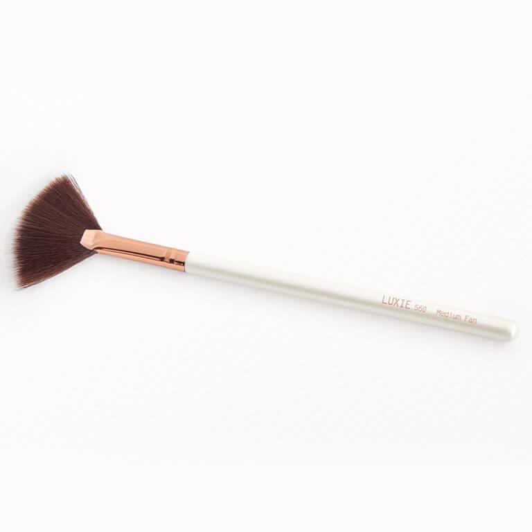 An image of the LUXIE BEAUTY 560 Medium Fan Flawless Brush and a model using a different fan brush to apply makeup Mobile