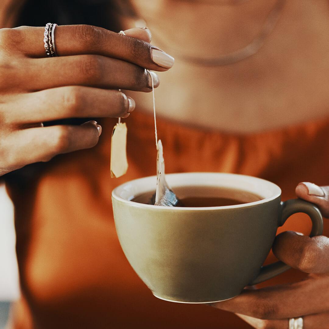 A closeup photo of a woman holding a cup of tea with teabag Desktop