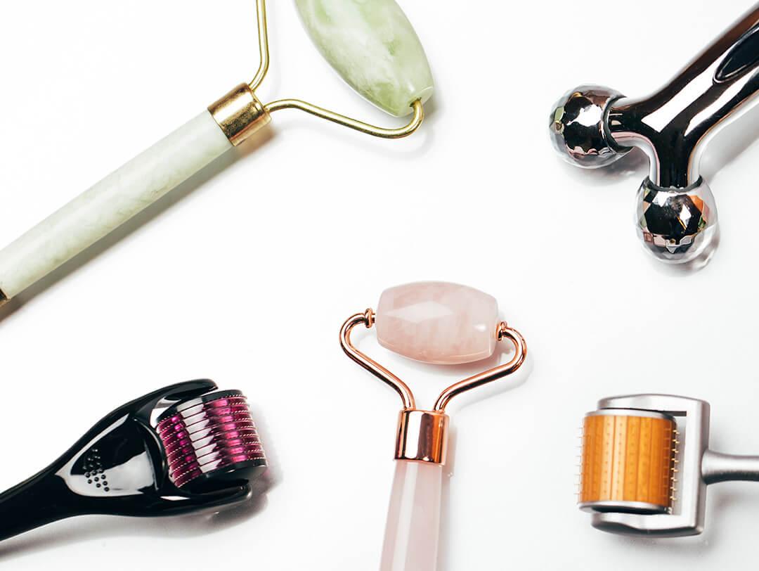 A flat lay of various face massage rollers neatly arranged on a white background Desktop