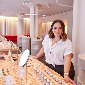 An image of Marta Topran leaning on a desk full of mirrors and beauty products Mobile