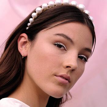 An image of a model wearing a white eyeliner look and a pearl-embellished headband Mobile