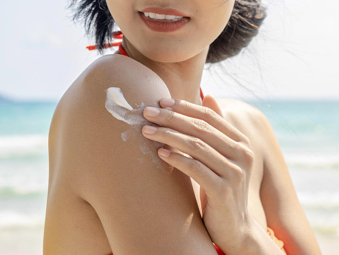 Close-up of a woman applying sunscreen on her shoulder Desktop