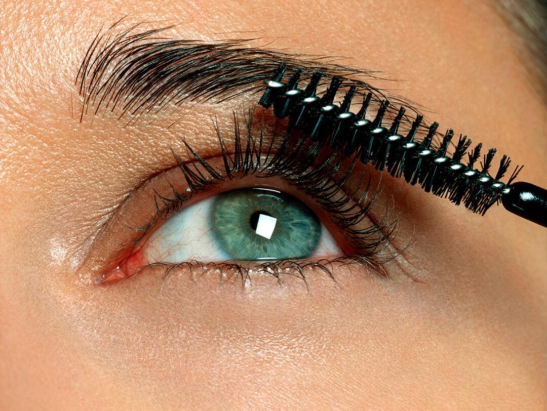 Close-up of a woman brushing eyelash and eyebrow with spoolie Desktop