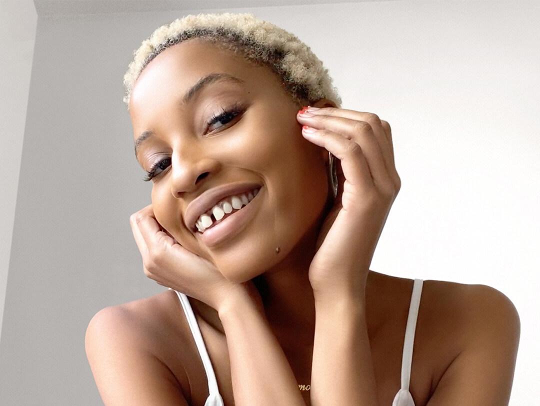 Close-up of a Black model with a no-makeup makeup look smiling and posing Desktop