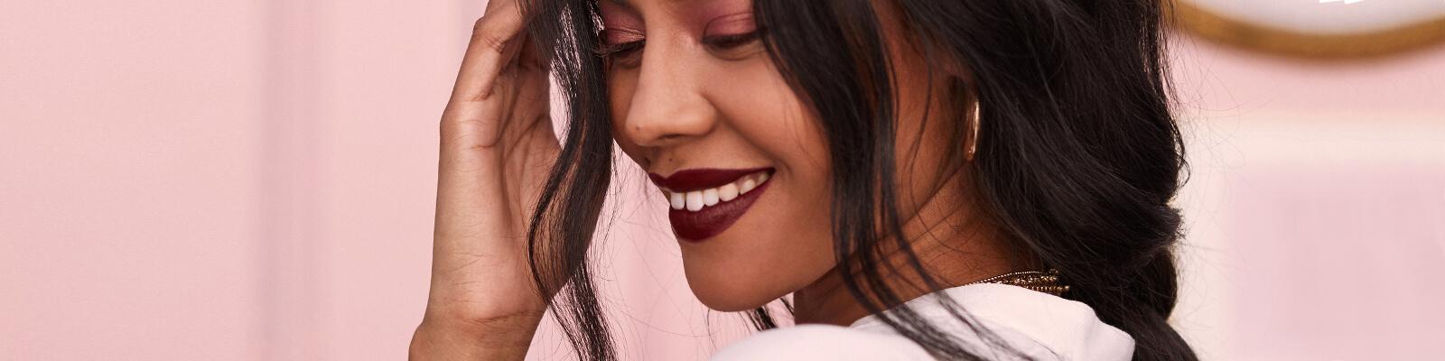An image of a model wearing hoop earrings and dark mauve lipstick showing her loose braids Desktop