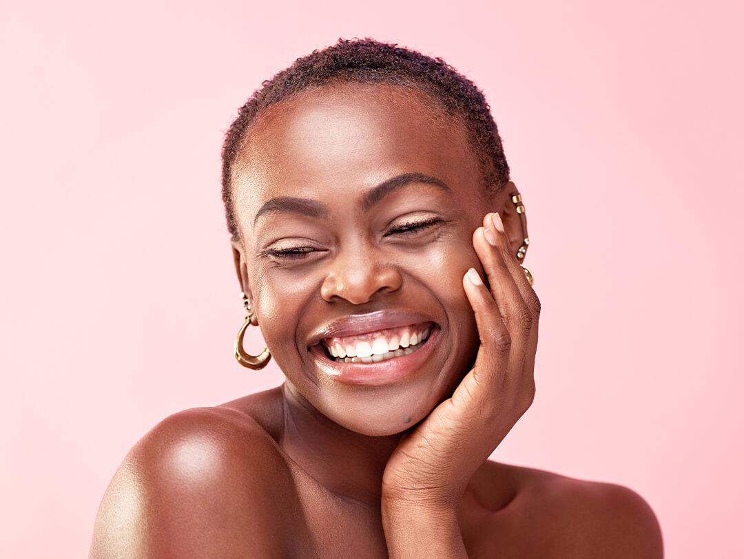 Studio shot of a Black woman posing against a pink background Desktop