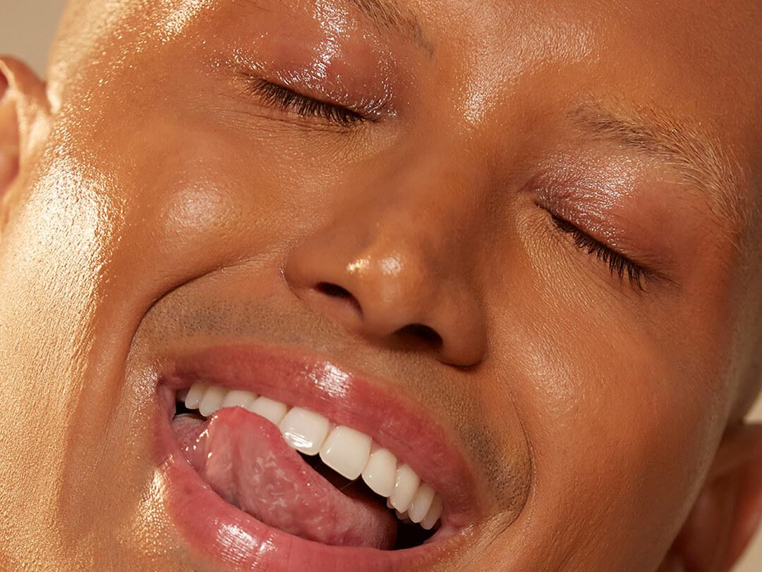 Close-up of a young man with dewy skin licking his teeth Desktop