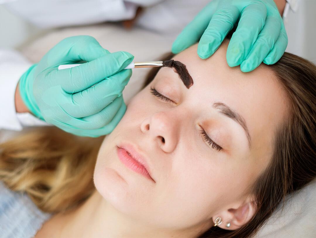 Close-up image of a woman having her eyebrows tinted by a specialist Desktop