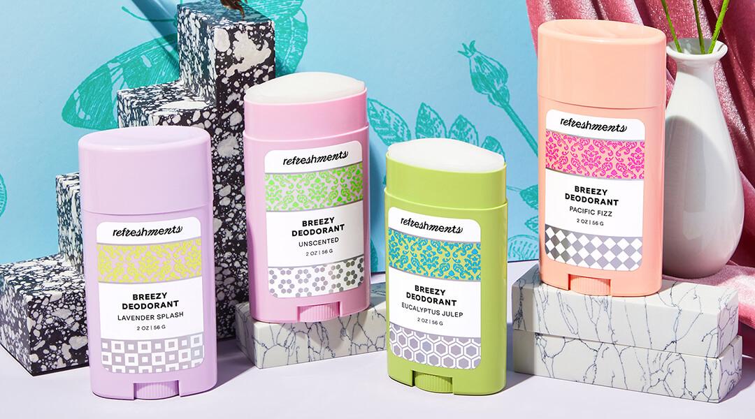 Flat lay image of four variants of REFRESHMENTS Breezy Deodorant against tropical background Desktop