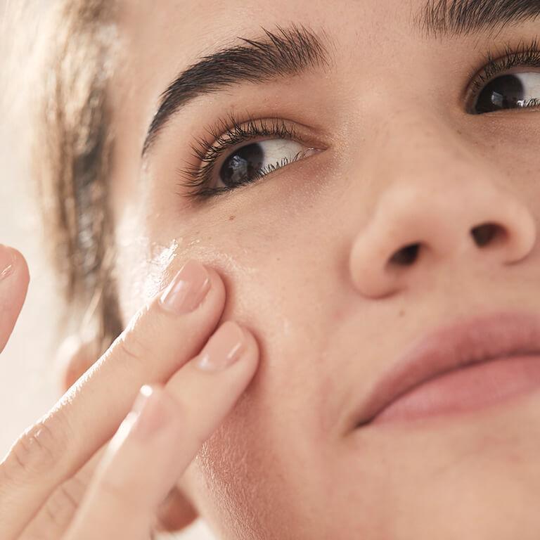 A closeup image of a model touching her cheek with two fingers Desktop