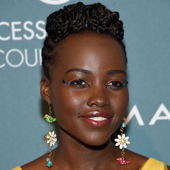 A close-up image of Lupita Nyong'o rocking a bold eyeshadow look, twisted top and cornrows hairstyle, and statement dangling earrings Mobile