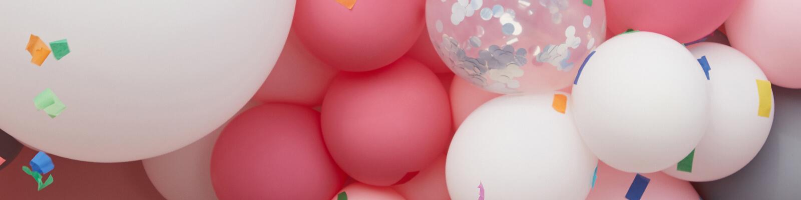 An image of pink and white balloons and confetti. Desktop