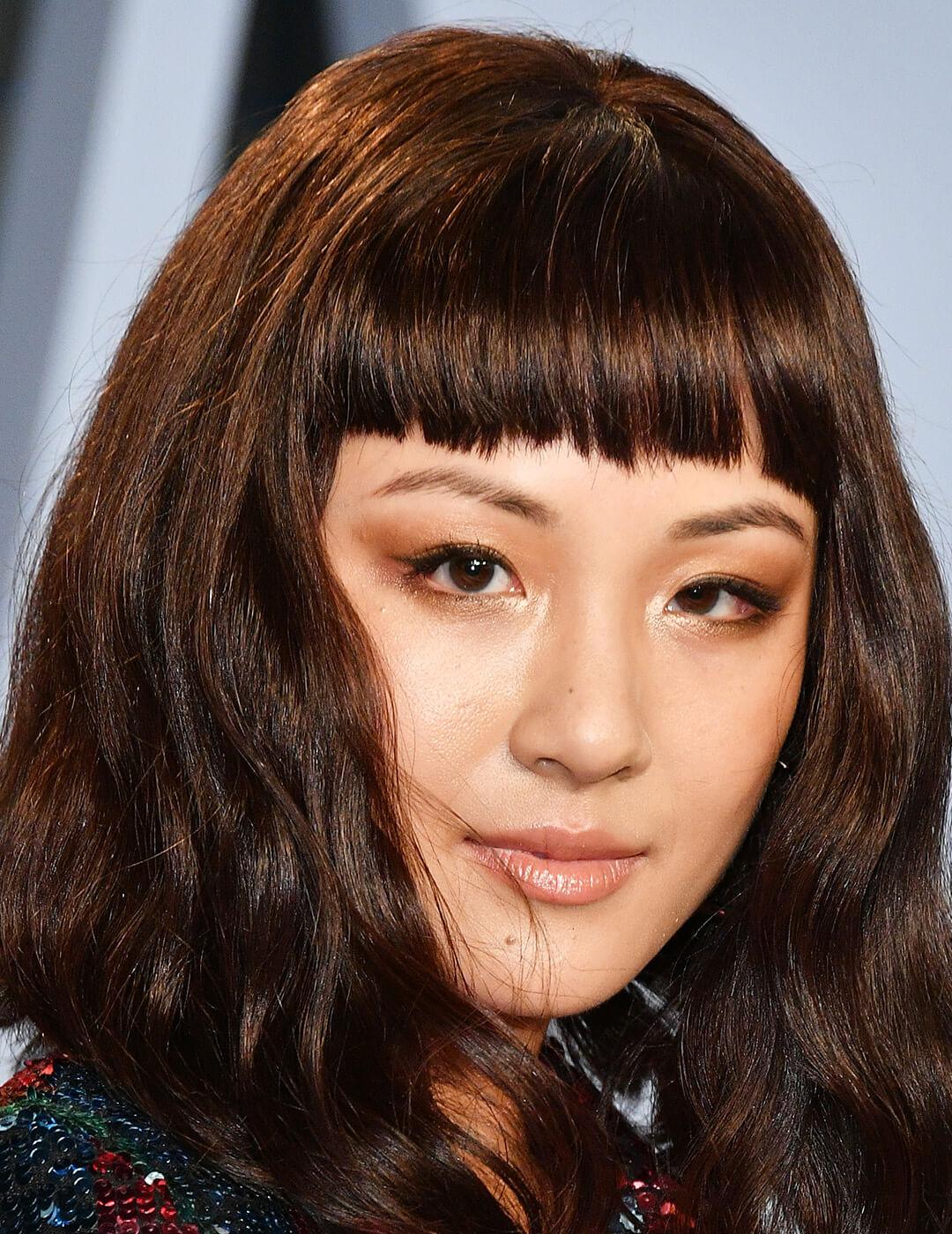 A photo of Constance Wu dons a stunning rainbow sequin long-sleeve robe dress featuring a sleek set of blunt bangs Mobile