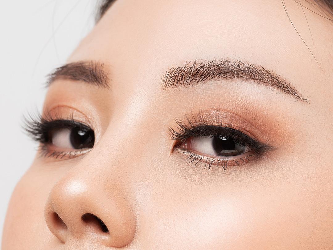 Close-up image of a woman with curled-up lashes against a white background Desktop