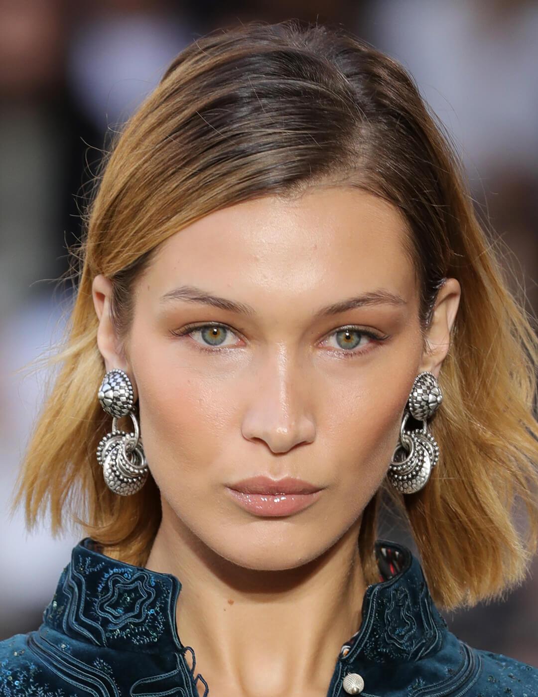 A photo of Bella Hadid with light makeup wearing metallic earrings Mobile