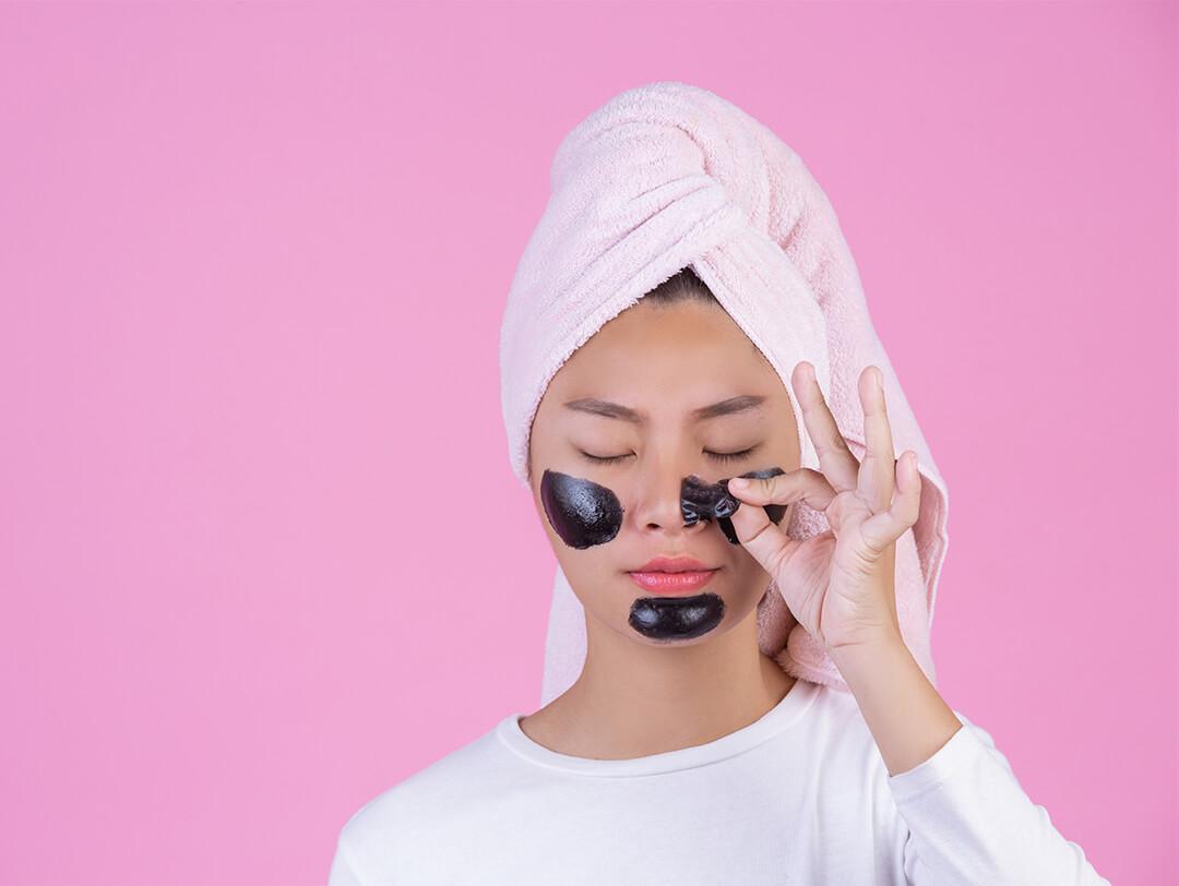 Image of a woman with hair wrapped in towel peeling off a charcoal mask Desktop