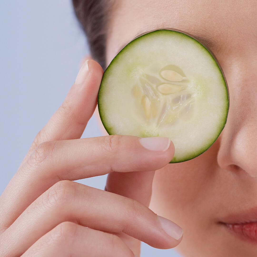Close-up image of a woman holding a cucumber slice to cover her eye Desktop