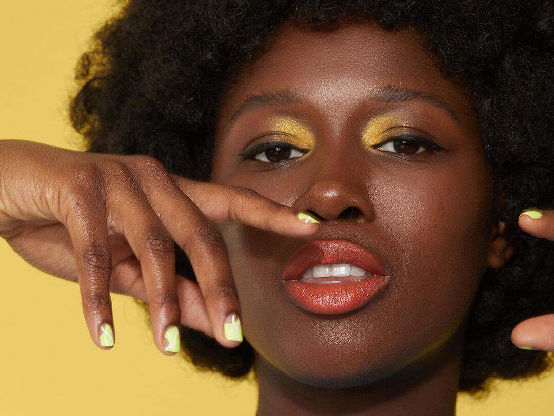 Close-up of a Black model rocking a yellow gold eye makeup look and slime yellow nail polish Desktop