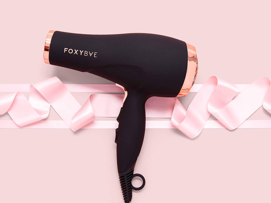 An image of a FOXYBAE hair dryer against a pink background. Desktop