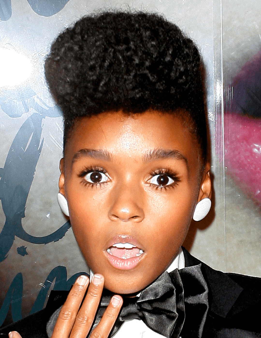 Janelle Monae in a quiff hairstyle, black suit and blow, and white stud earrings looking shocked Desktop