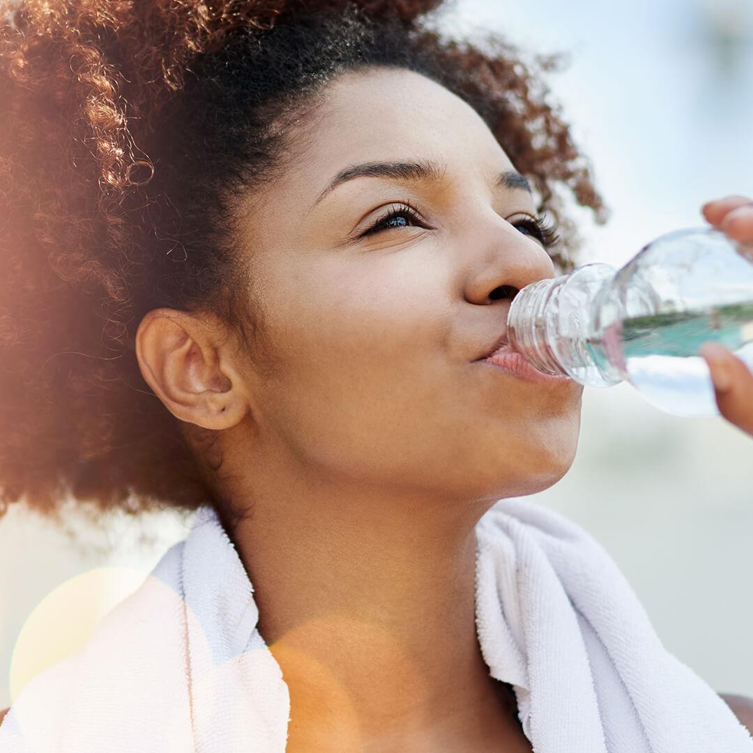 Photo of a woman drinking a bottle of water with a towel on her neck Desktop