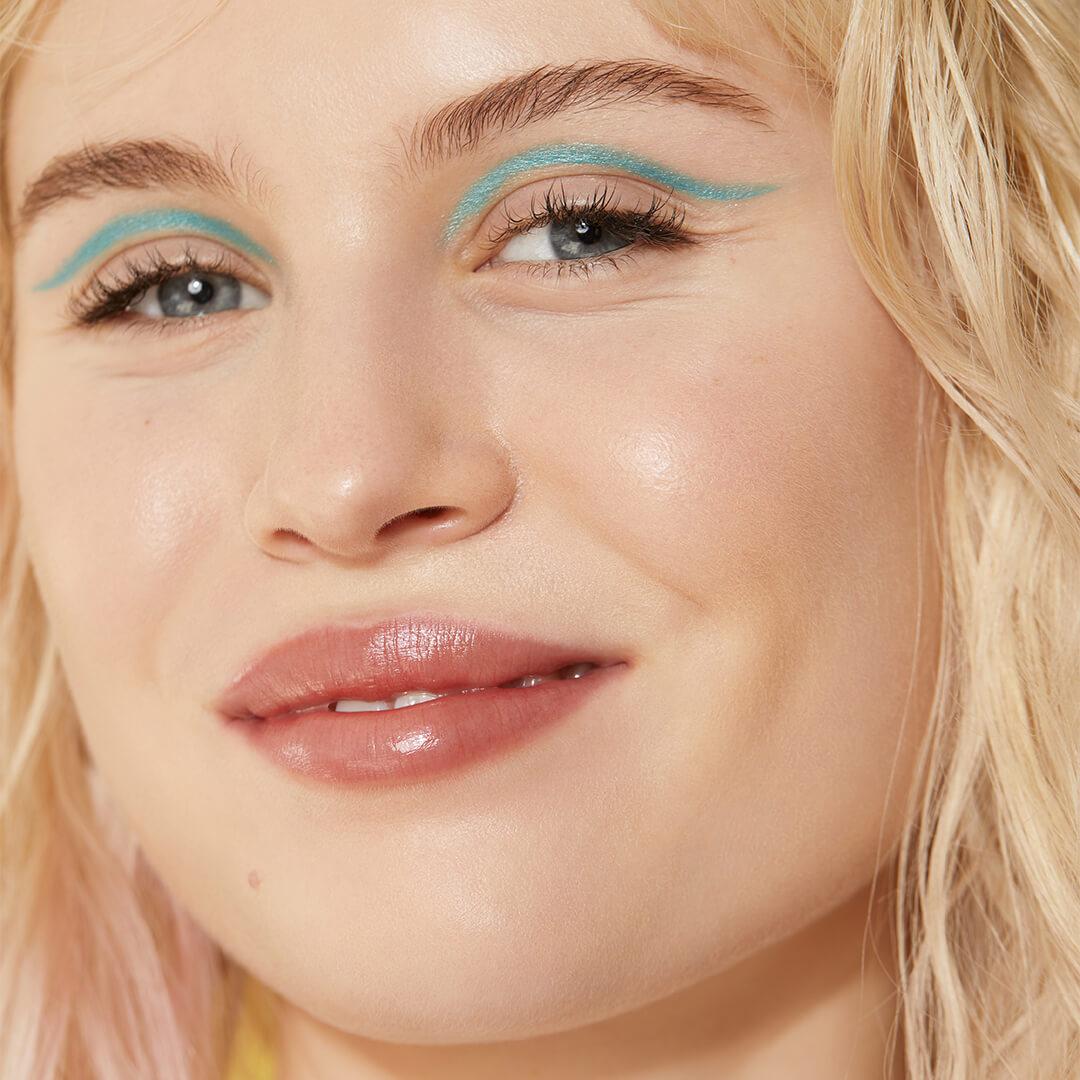Close-up of a smiling model rocking a green eyeliner makeup look Desktop