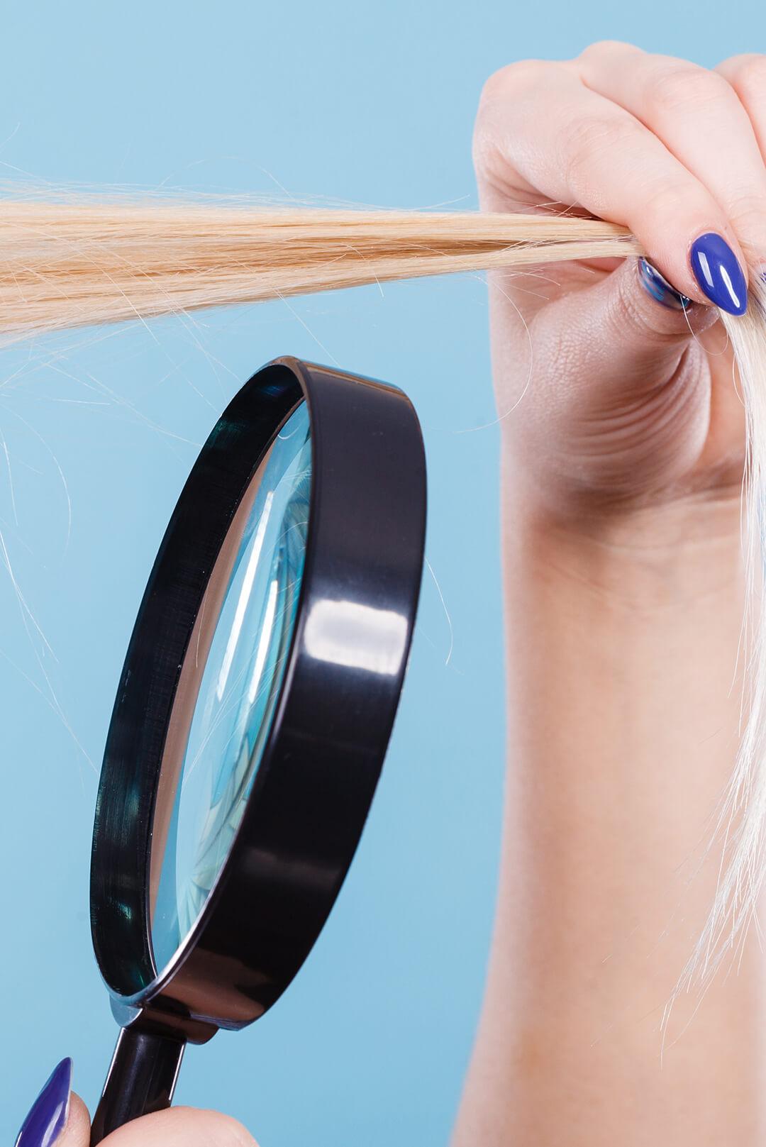 Woman's hands holding her hair and a magnifying glass Desktop